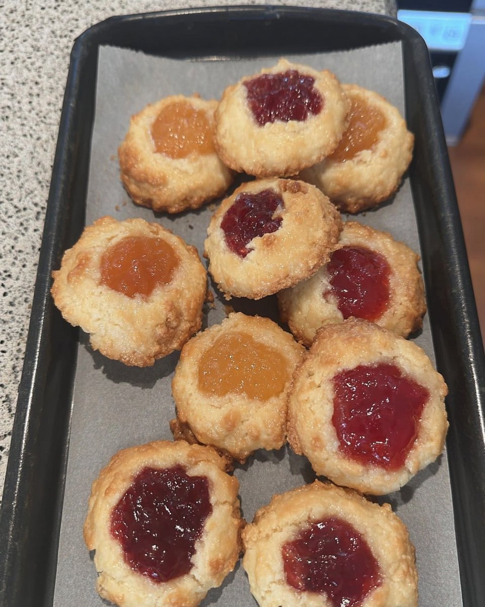 A batch of golden apricot thumbprint cookies on a cooling rack