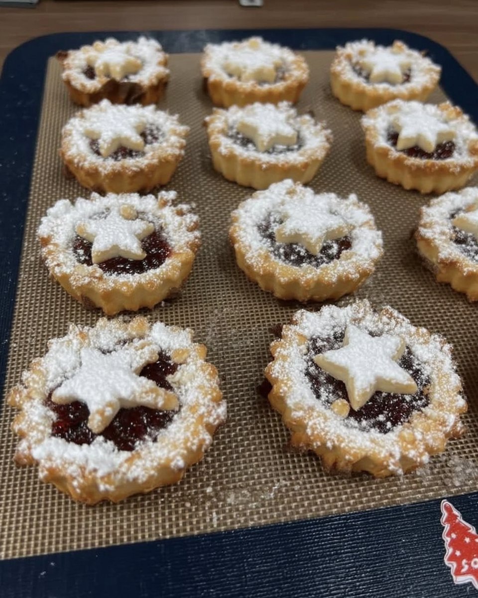 Finished raspberry linzer cookies being dusted with powdered sugar.