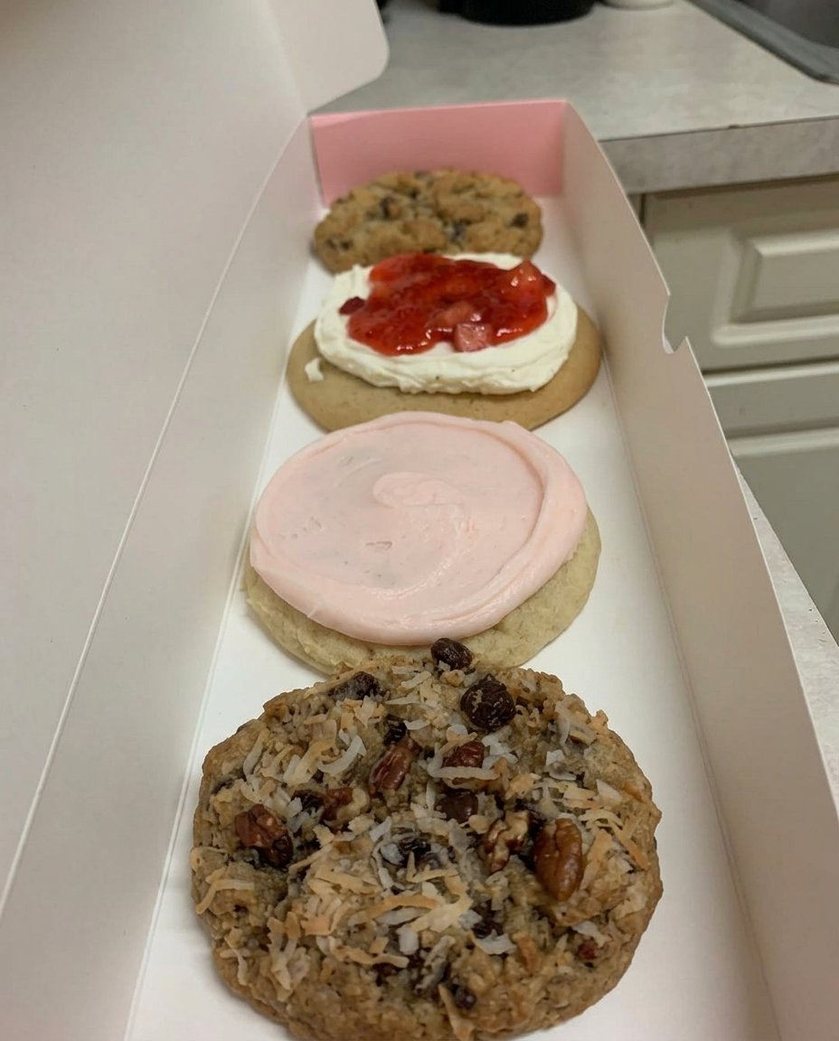 A stack of giant chocolate chip cookies next to a glass of milk
