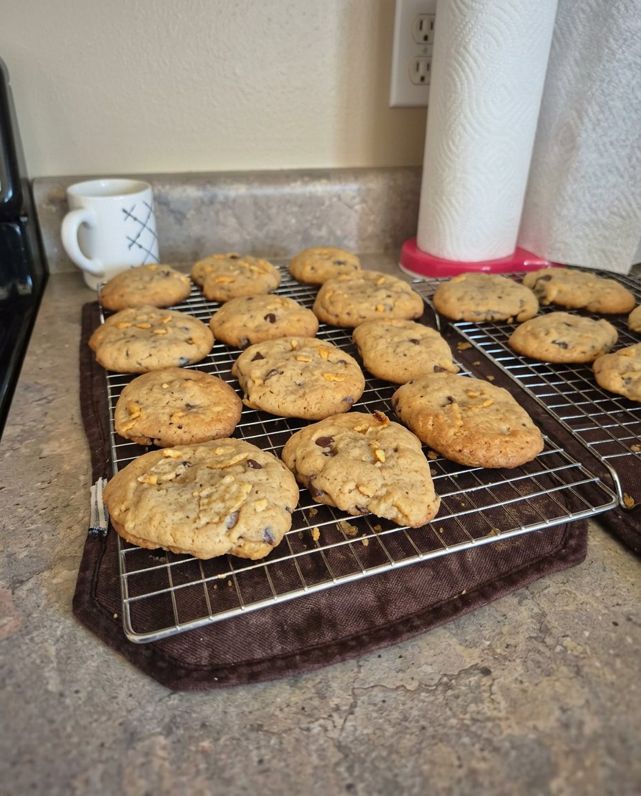 A plate of potato chip chocolate chip cookies next to a glass of milk.