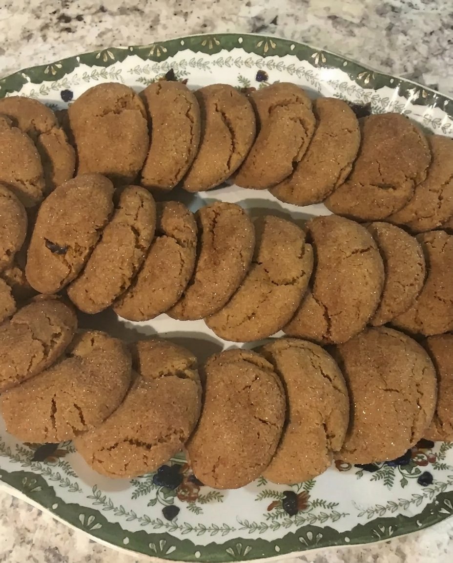 Gingersnap cookies cooling on a wire rack with golden cracked tops