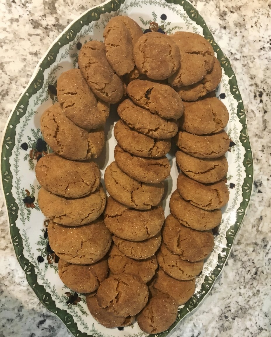 A plate of gingersnap cookies served with a cup of aromatic tea